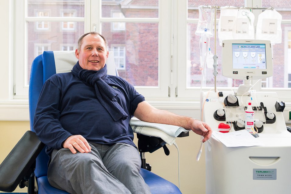 UKM | Blutspender auf einem blauen Stuhl, sein Arm liegt auf der Lehne. Daneben ein Apharesegerät mit Bildschirm